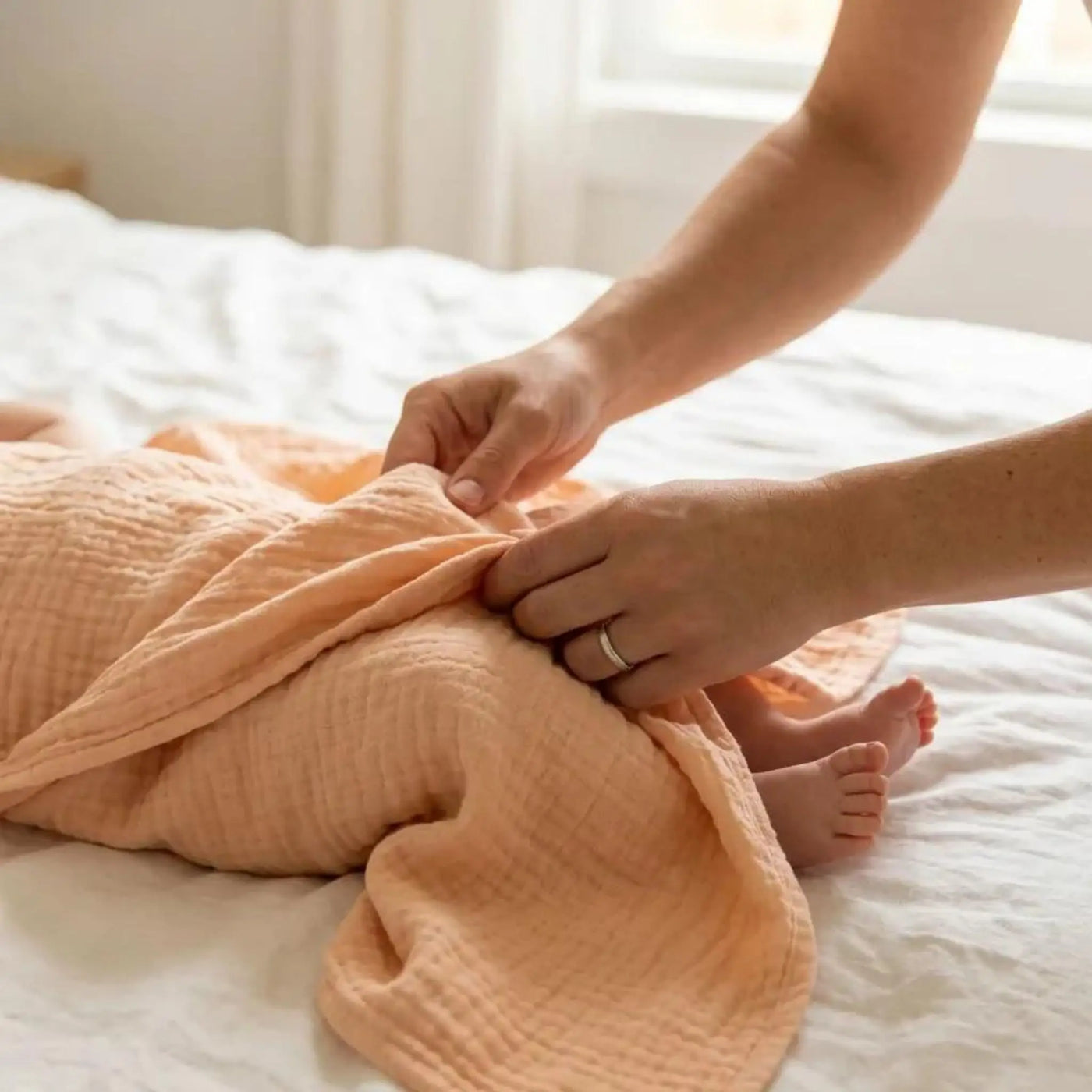 Somon renkli baskısız müslin bebek örtüsü kullanan anne ve bebek